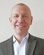 Das Foto zeigt einen lächelnden Mann.